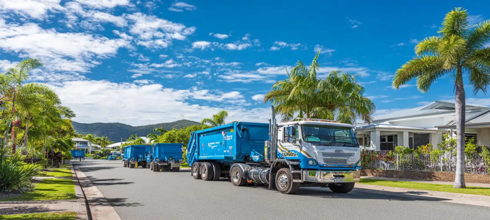 Multiple blue skip bin trailers parked along a roadside showcasing skip bins Mackay QLD waste management solutions